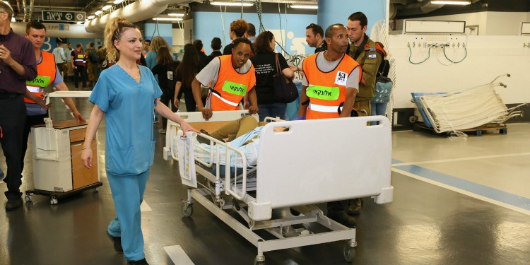 Three hospital workers transferring a patient on a medical bed.