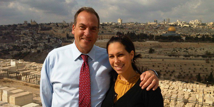 Yechiel in blue button up and red tie next to Yael in black cardigan and mustard top.