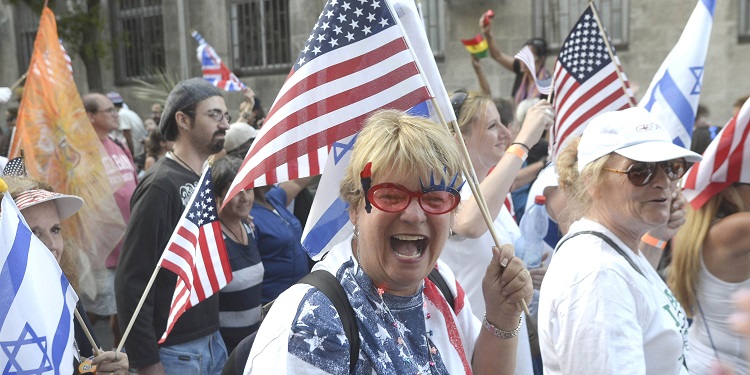 Women smiling at the camera while waving American flags.