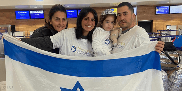 Family holding an Israeli flag at an airport, representing hope, unity, and support for Jewish communities and families in need worldwide.