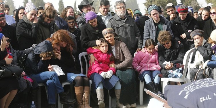 Group of people standing behind a line of people that are sitting in chairs.