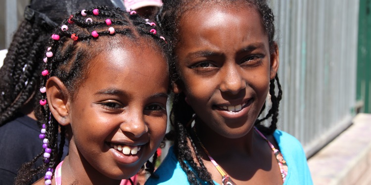 Two young girls during summertime smiling at the camera.