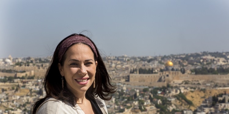 Yael Eckstein smiling at the camera while Jerusalem is behind her.