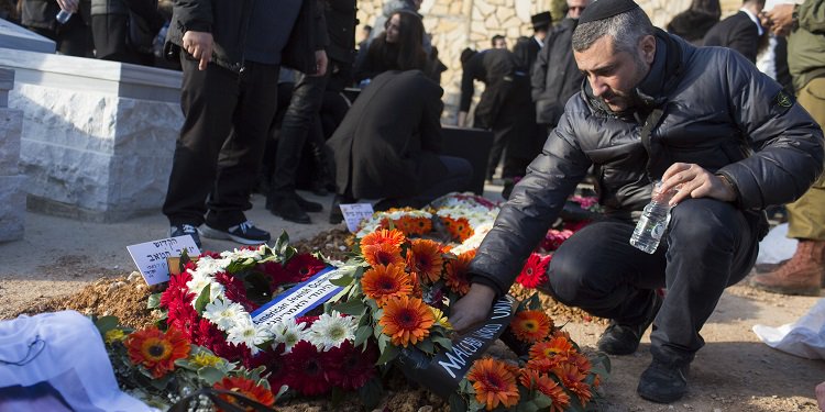 Man wearing a kippah laying down funerals for a memorial.