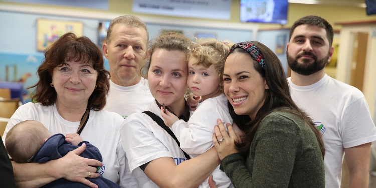 Yael Eckstein smiling with a family who just made Aliyah.