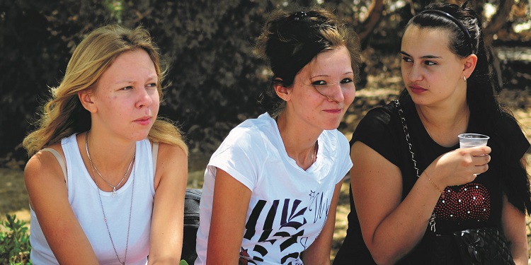 Three young women sitting together outside.