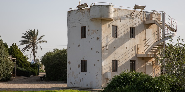 Old white building by a dirt road.