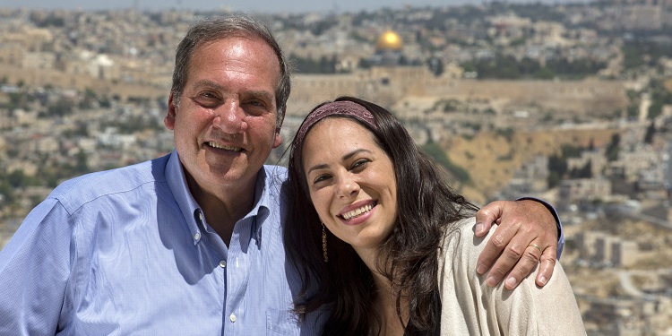 Yael Eckstein sitting next to her father with Jerusalem in the background.