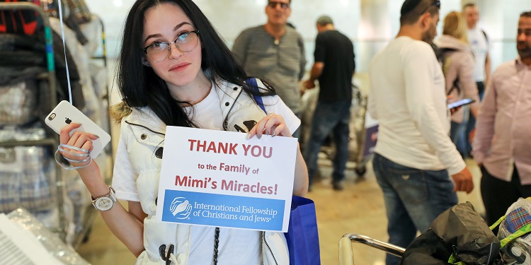 A woman holding an IFCJ branded thank you sign.