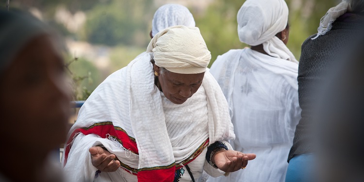 Ethiopian woman in a robe bowing down.