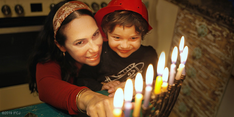 Yael Eckstein lights Hanukkah menorah with son