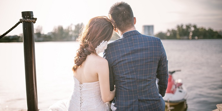 Young couple who just married looking at a body of water.