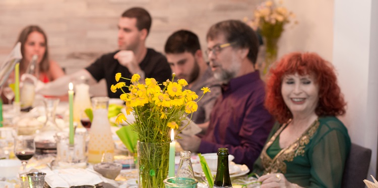 Half of a dinner table with five people sitting at it smiling.