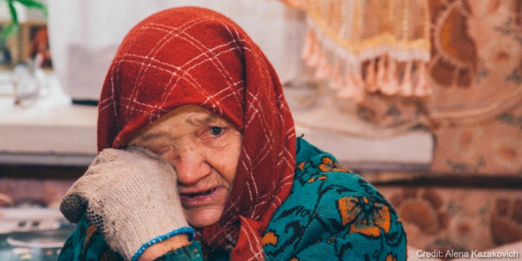 Elderly Jewish woman wiping her face while crying.
