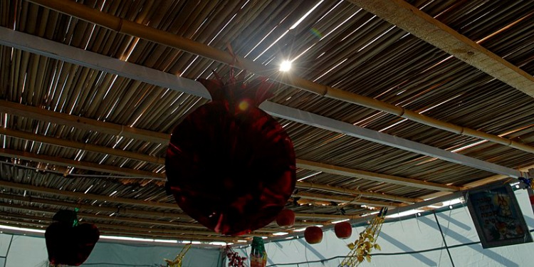 Paper lantern hanging from a wooden ceiling.