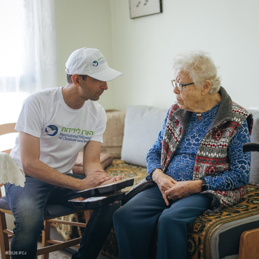 Elderly woman receiving support and companionship from a volunteer in a cozy home setting.