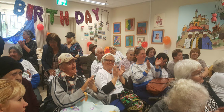 Several adults gathered for an 85th birthday celebration.