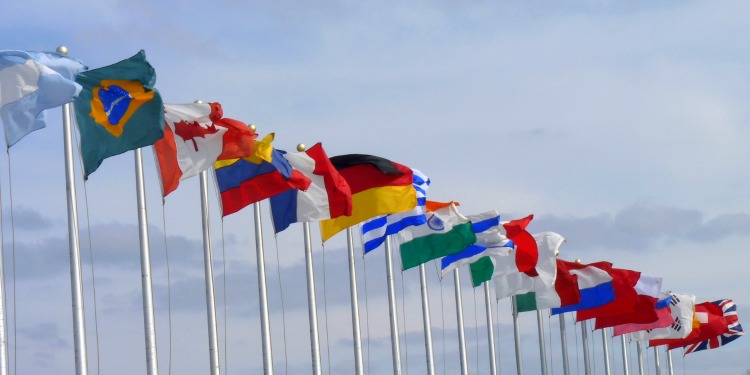 Several flags on poles flying in the wind.