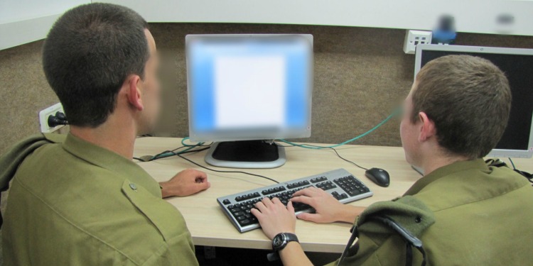 Two soldiers working on a computer together.