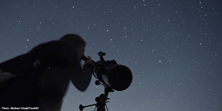 A Person using a telescope during a meteor shower