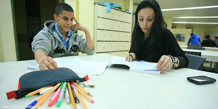 A teacher and student sitting at a table with pencils