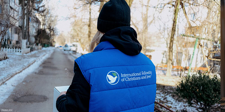 A woman wearing a black hat and a vest with the IFCJ logo
