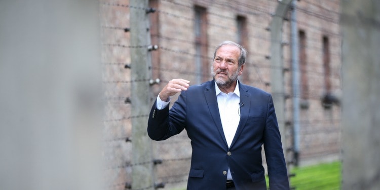 Rabbi Eckstein looking up while standing in the middle of a metal fenced in pathway.