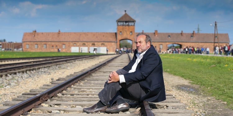 Rabbi Eckstein sitting on empty train tracks looking off into the distance.