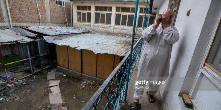 Man in white robe standing on a balcony in Afghanistan.