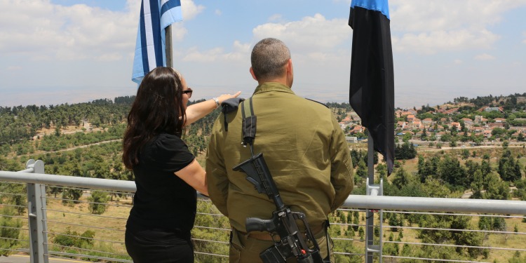 Yael Eckstein at the Lions of the North Air Defense Battery. overlooking land. flag. back of soldier's head.ÿ