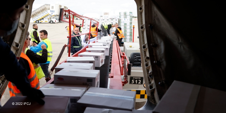 People going through humanitarian aid boxes on an airlift.