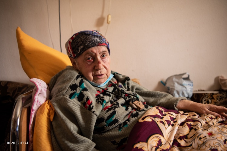 Elderly Jewish woman lying sick in bed looking directly at the camera
