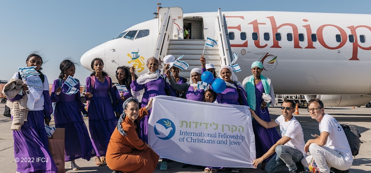 Yael Eckstein and several people who've just made Aliyah from Ethiopia in front of a plane.