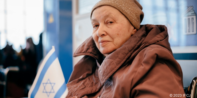 Elderly Jewish Ukrainian Refugee holding Israel's flag.