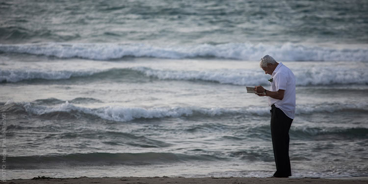 An Orthodox Jewish man praying while performing the Tashlich ceremony over the beach