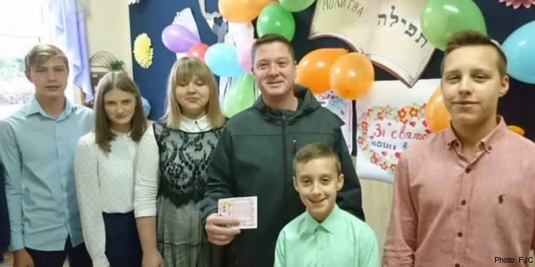 A group of people standing in front of a wall with balloons.