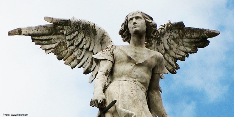 An angelic statue with a blue cloudy sky behind it.