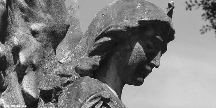 Black and white image of an angelic statue looking down.