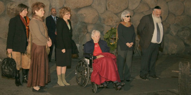 Six people standing alongside a woman in a wheelchair for a ceremony.