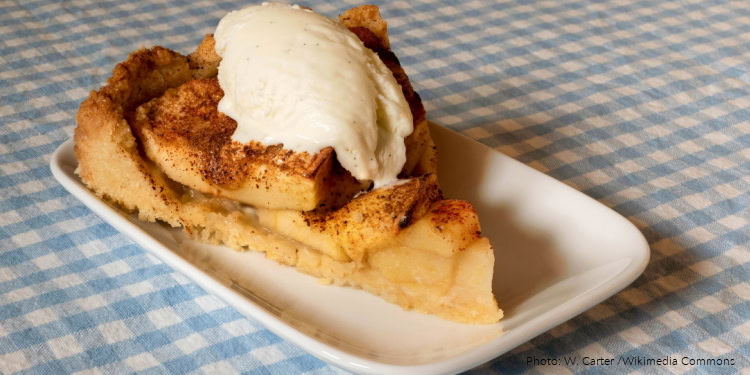 A slice of traditional Rosh Hashanah apple cake topped with vanilla ice cream on a white plate, symbolizing sweetness for the new year.