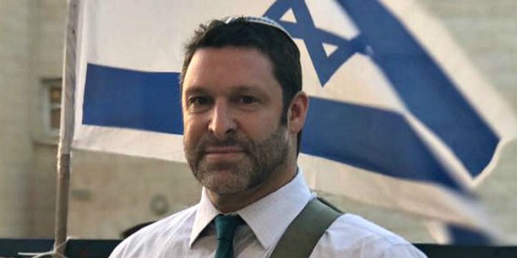 Man wearing a kippah in front of the Israeli flag.