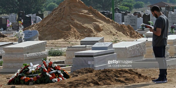 Man standing in a grave site.