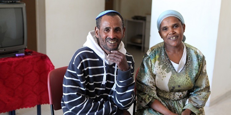 Avitch and Asmarah, two IFCJ recipients sitting happily together in a living room.