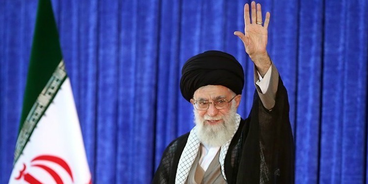 A man waving to a crowd with a flag and a blue background behind him.