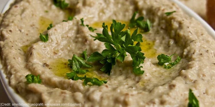 Close up image of baba-ganouj with parsley and oil on top.