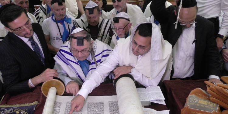Several men reading through a scripture roll.