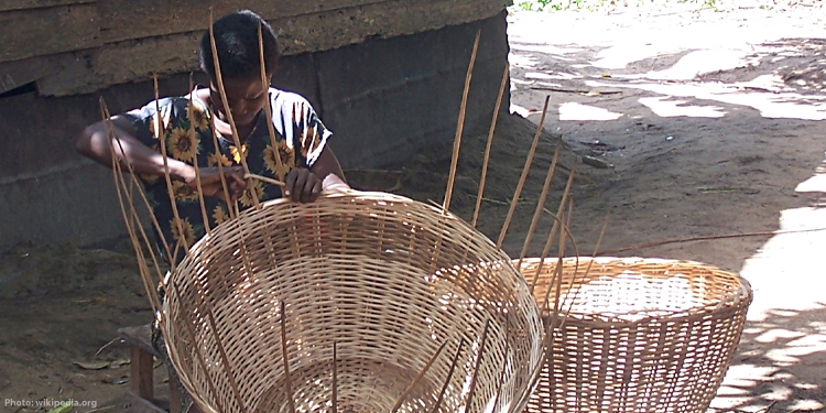 Image of a woman weaving a basket