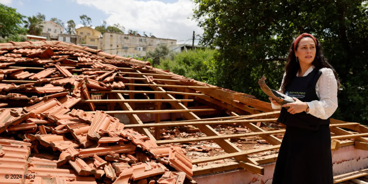 Yael stands on damaged Beit Batya Soup Kitchen roof.