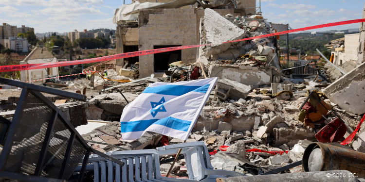 Israeli flag flying over rubble and destruction in a war-torn area, symbolizing resilience and hope amidst devastation.