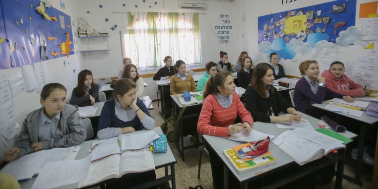 Several young women paying attention to the teacher in their classroom.